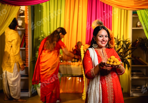 Preview: Holding laddu thali with smile, girl invites to join Ganesh puja as family decorates in background