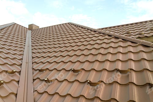 Preview: Detail view of house rooftop covered with brown metal tile sheets.