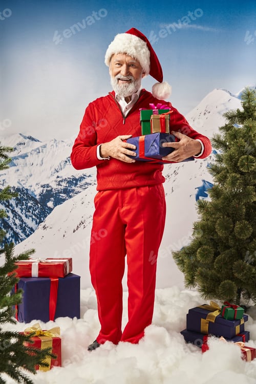 Preview: joyful Santa in red hat standing and posing with presents and smiling at camera, winter concept