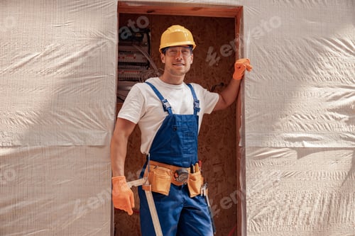 Preview: Joyful male builder standing in doorway at construction site