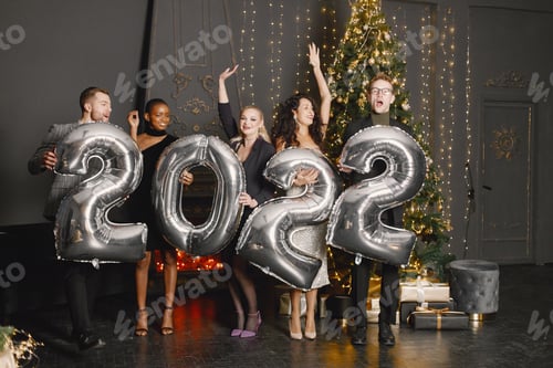 Visualização: Amigos do sexo masculino e feminino em pé com balões 2022 para a celebração do Ano Novo
