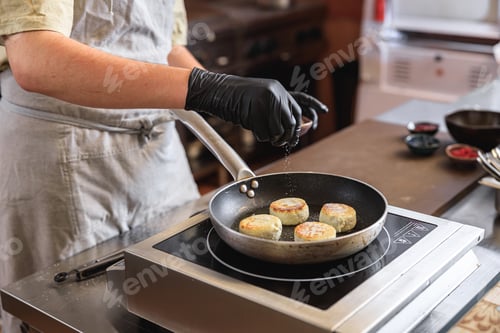 Preview: Professional Chef preparing cheesecakes on frying pan for breakfast in restaurant kitchen