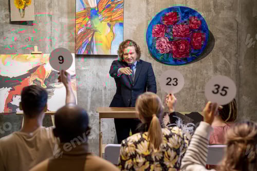 Preview: Male auctioneer pointing at one of people with auction paddles