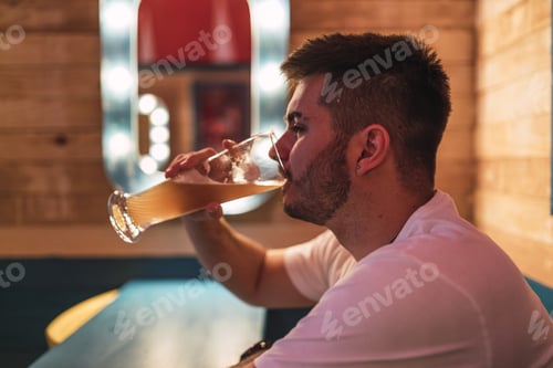 Preview: Side view of a young European male drinking beer in the pub