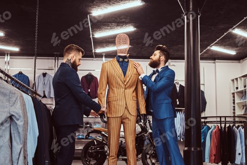 Preview: Two stylish shop assistants elegantly dressed working in a menswear store.