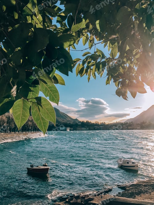 Preview: Fresh green leaves, tree, boats on the lake, mountains, nature, sunset, spring landscape, water