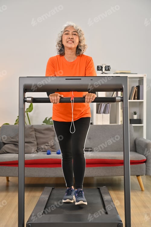 Preview: Full length shot of middle aged woman in sport clothes walking on a treadmill indoors.