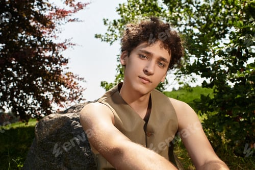 Preview: Curly-haired man enjoying the sunny day in a vibrant park setting