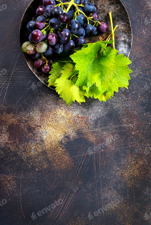Fresh Grapes and Green Leaves on Rustic Plate