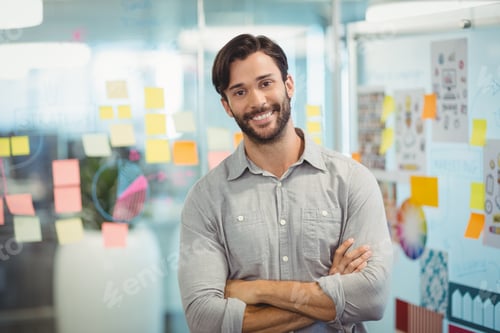 Preview: Male business executive standing with arms crossed in office