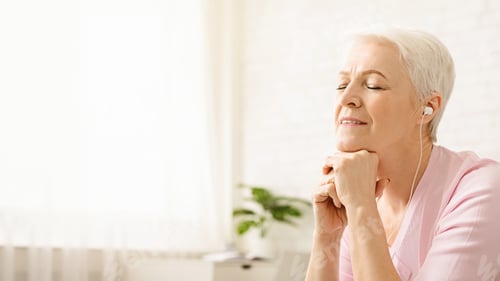 Preview: Senior woman enjoying music at home with closed eyes