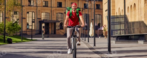 Preview: Delivering food to customers. Full length of a young cheerful caucasian male courier with thermo bag