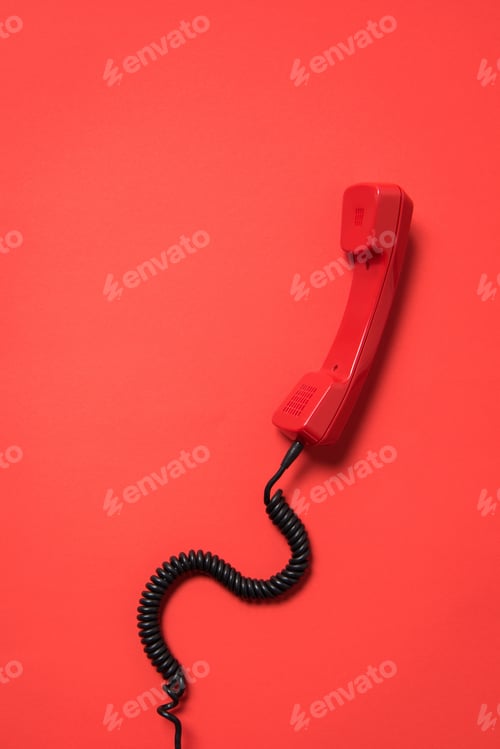 Preview: Close-up view of vintage telephone handset with curly cord isolated on red