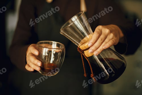 Preview: Professional female barista in black uniform making drip coffee