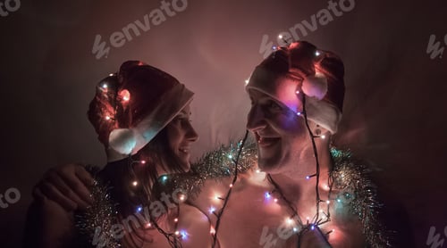 Preview: Romantic Couple Wearing Christmas Hats and String Lights