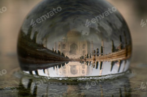 Preview: Closeup shot of Taj Mahal reflection in a glass ball in the water with a blurred background