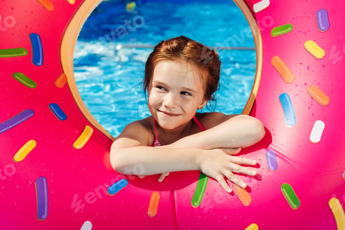 Preview: adorable little child with inflatable ring in shape of donut in swimming pool
