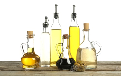 Preview: Salad dressings and olives on wooden table against white background