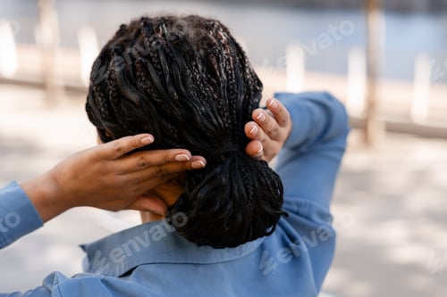 Preview: Woman Styling Braided Hair in an Urban Setting