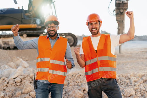 Preview: Happy construction workers celebrating success at worksite