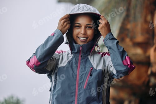 Preview: Shot of a woman wearing her rain jacket while out hiking