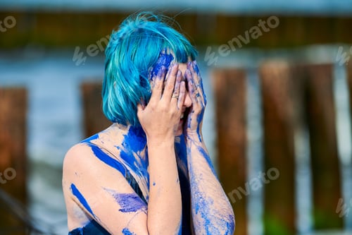 Preview: Artistic blue-haired woman performance artist in dress smeared with blue gouache paints on her body