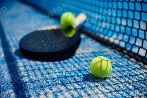 Preview: Paddle tennis equipment on the ground at outdoor court.