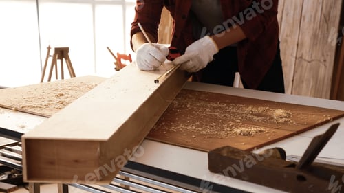 Preview: Carpenter using tape measure to scale size of board.
