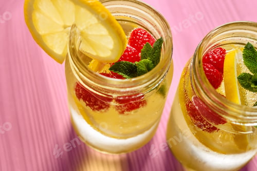 Preview: soda with lemon, berries and mint on pink table