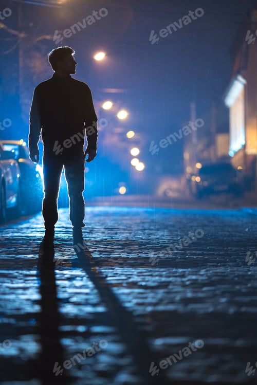 Preview: The man stand on the rain road. Evening night time. Telephoto lens shot.