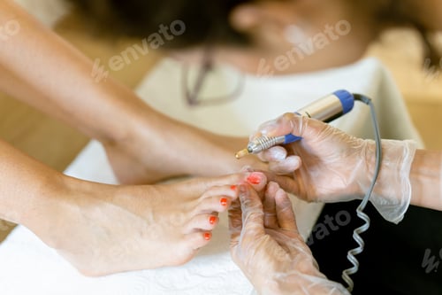 Preview: Beautician giving a pedicure painting her client's nails in a beauty centre