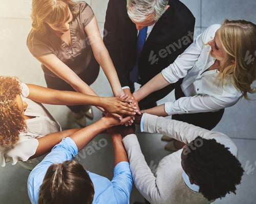 Preview: High angle shot of a group of colleagues joining their hands in solidarity