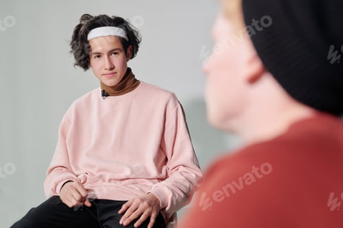 Preview: Serious man in powdery pink pullover and white headband interacting with vlogger