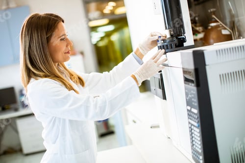 Preview: Young female scientist in a white lab coat putting vial