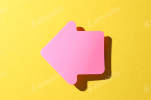 Preview: One pink paper arrow on yellow background, top view