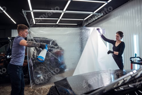 Preview: Man and Woman Applying Protective Film to Vehicle