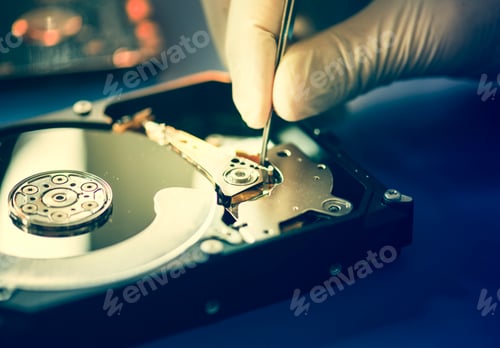 Preview: Closeup of hands with tweezers and computer hard disk