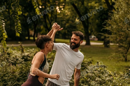 Preview: Happy couple giving high five while running in park
