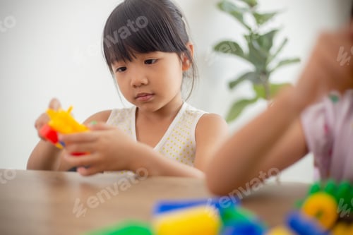 Preview: Adorable little girl playing toy blocks in a bright room