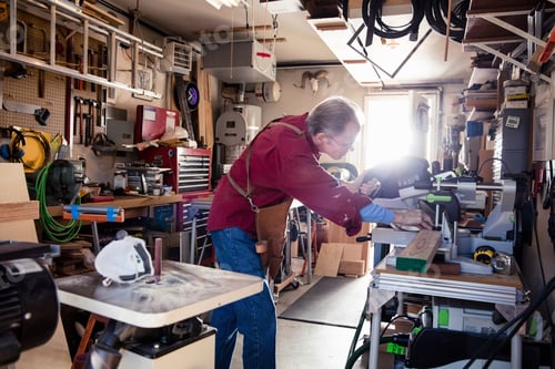 Preview: Senior man sawing with circular saw in carpentry workshop