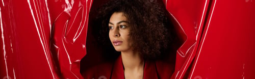 Preview: Curly woman in trendy outfit celebrates love on Valentines Day in bright studio