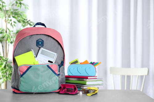 Preview: Stylish backpack with different school stationery on table indoors. Space for text