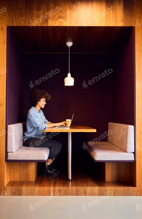 Preview: Young Businesswoman In Modern Open Plan Office Working On Laptop In Seating Pod