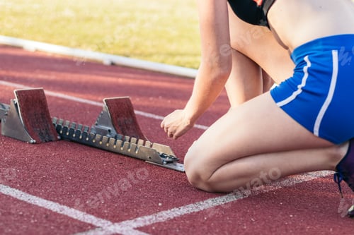 Preview: A female athlete getting ready to run on an athletics track.