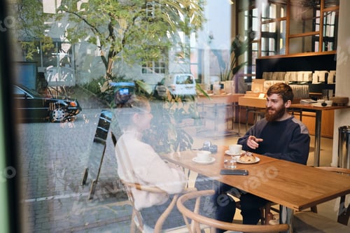 Preview: Young beautiful couple happily talking during coffee break in cafe