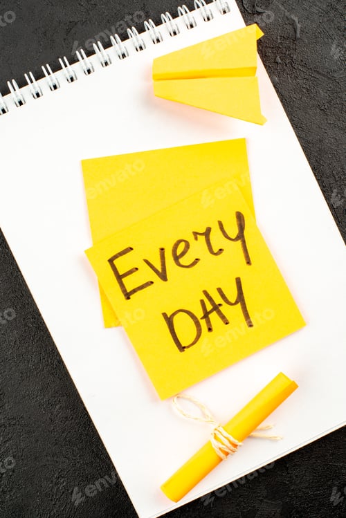 Preview: top view every day written on sticky note scroll sticky note on spiral notepad on dark background