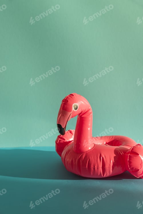 Preview: Pink Flamingo Shaped Pool Float on Turquoise Water under Sunlight. Front view