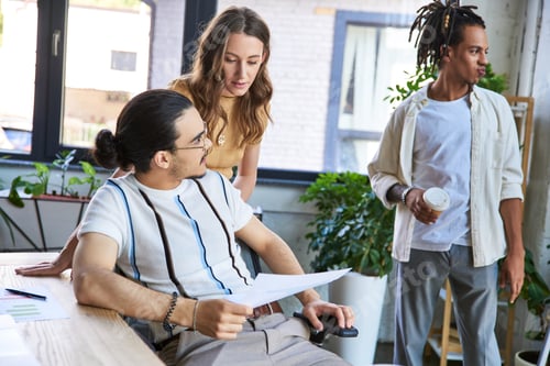 Preview: team lead with documents sitting near multiethnic colleagues working on startup in office, planning