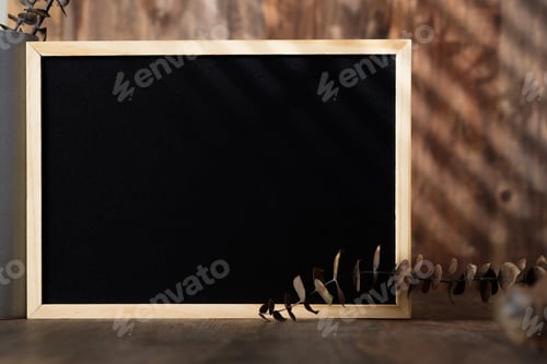 Preview: blank blackboard frame with kitchenware on wood table with sunlight