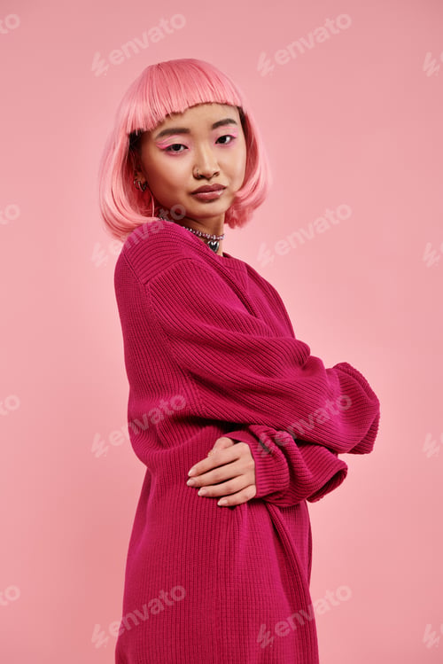 Preview: gentle asian young woman with pink hair in sweater outfit hugging herself and looking to camera